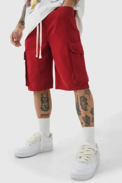 Shop boohooMAN Baggy Fit Elasticated Waist Extended Drawcord Cargo Shorts red