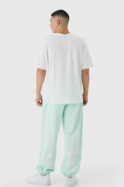 Shop boohooMAN Oversized Worldwide Spray Wash Printed Joggers turquoise