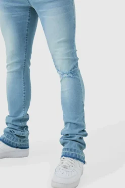 Shop boohooMAN Skinny Stacked Flared Jeans With Knee Rip light blue