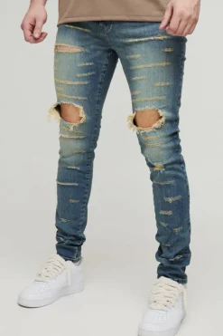 Shop boohooMAN Tall Extreme Rip Busted Knee Skinny Jeans mid wash